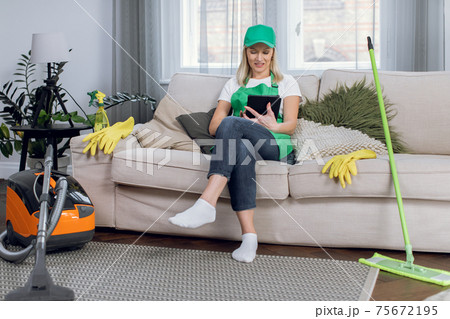 Relaxed housekeeper using tablet while sitting on couch Relaxed housekeeper using tablet while sitting on couch 75672195