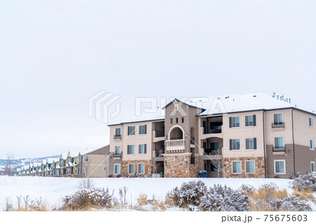 Apartments and townhouses on a scenic snowy neighborhood landscape in winter Apartments and townhouses on a scenic snowy neighborhood landscape in winter 75675603