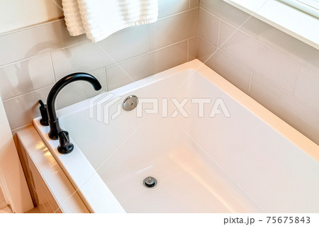 Rectangular built in bathtub with black curved faucet inside bathroom of home Rectangular built in bathtub with black curved faucet inside bathroom of home 75675843