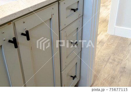 Vanity cabinet with black handles and white countertop inside bathroom 75677115