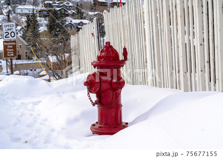 Vibrant red fire hydrant against snow and hill homes at Park City Utah in winter Vibrant red fire hydrant against snow and hill homes at Park City Utah in winter 75677155