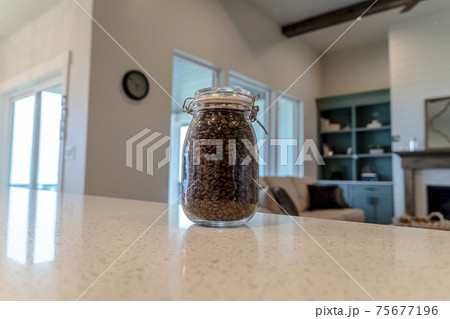Jar of coffee beans on the glossy white counter top inside a home kitchen 75677196
