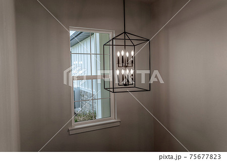 Geometric chandelier hanging from the ceiling of home against window and wall Geometric chandelier hanging from the ceiling of home against window and wall 75677823