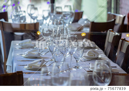 Wineglasses and tableware arranged on a table setting for a social gathering Wineglasses and tableware arranged on a table setting for a social gathering 75677839