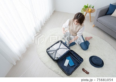 リビングで旅行の準備をする若い女性 リビングで旅行の準備をする若い女性 75681054