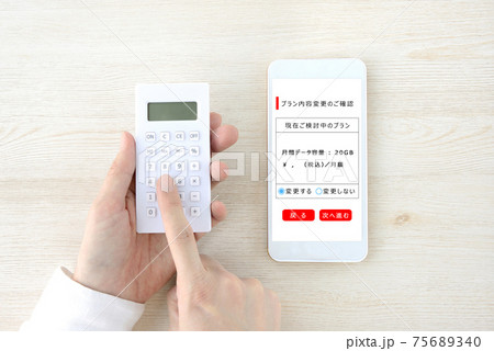 スマホのプラン変更の計算をする人物の手 75689340