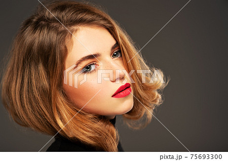 Closeup portrait of an young adult girl with medium length hair.  Photo of a fashion model posing at studio. Pretty young woman with red lips looking at camera. Beauty portrait. 75693300