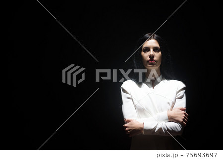 model in a white suit on stage in a beam of white light model in a white suit on stage in a beam of white light 75693697