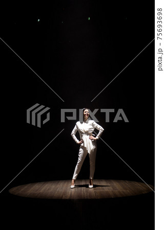model in a white suit on stage in a beam of white light 75693698