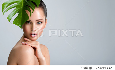Beautiful woman with green leave near face and body. Closeup girl's face with green leave. Skin care beauty treatments concept. Beautiful woman with green leave near face and body. Closeup girl's face with green leave. Skin care beauty treatments concept. 75694332