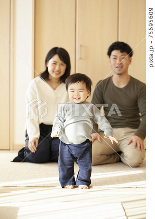 歩く赤ちゃんと見守る両親の写真素材