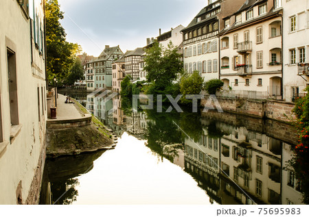 Strasbourg, France, August 2019. The historic center offers the view of pleasant and relaxing glimpse: the characteristic period houses are reflected on the water mirror of the canals. Strasbourg, France, August 2019. The historic center offers the view of pleasant and relaxing glimpse: the characteristic period houses are reflected on the water mirror of the canals. 75695983