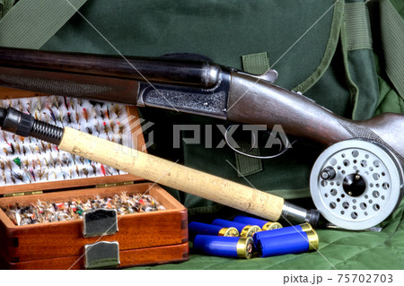 Shotgun with Fishing Rod and Fly Box and Fly Reel and Cartridges with Game Bag on Outdoor Coat 75702703