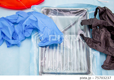 Sterile medical instruments in packaging and blue and black disposable gloves Sterile medical instruments in packaging and blue and black disposable gloves 75703237