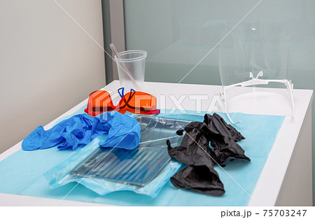 Sterile medical instruments in packaging and blue and black disposable gloves Sterile medical instruments in packaging and blue and black disposable gloves 75703247