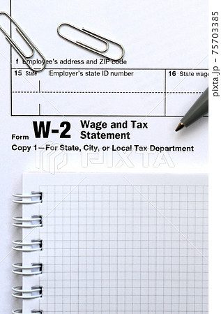 The pen and notebook on the tax form W-2 Wage and Tax Statement. The time to pay taxes The pen and notebook on the tax form W-2 Wage and Tax Statement. The time to pay taxes 75703385