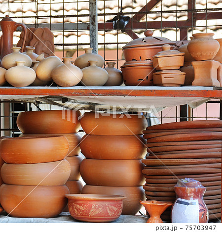 Shelves with ceramic dishware in pottery workshop. 75703947