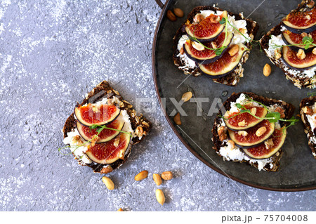 Canape, crostini or bruschetta with figs, bread, cheese on metal tray top view 75704008