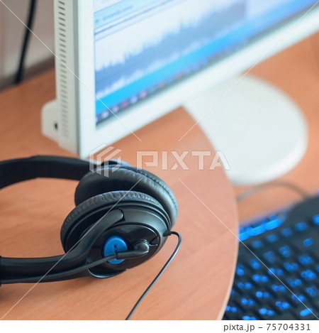 Big black headphones lie on the wooden desktop of the sound designer 75704331