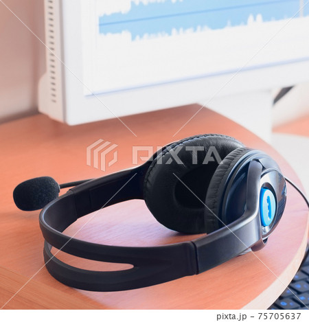 Big black headphones lie on the wooden desktop of the sound designer 75705637