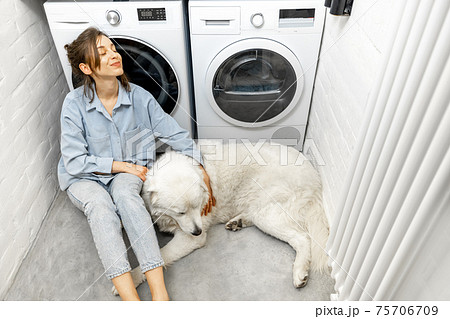 Woman with a dog in the laundry at home 75706709