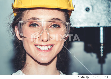 Young woman factory worker close up portrait in manufacturing job factory Young woman factory worker close up portrait in manufacturing job factory 75706931