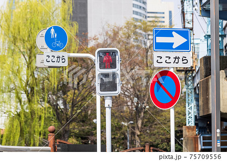 都会の交差点の歩行者用信号と交通標識の写真素材