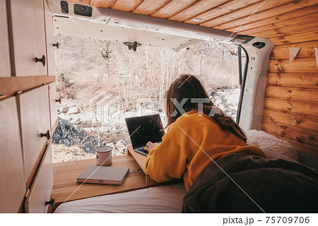 Vanlife - Young woman working on notebook in camping van surrounded by nature Vanlife - Young woman working on notebook in camping van surrounded by nature 75709706