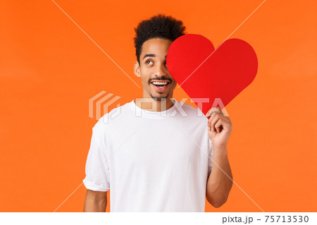 Dreamy handsome african-american guy found true love, giving valentines card to lover, looking upbeat up thoughtful, imaging perfect date, express own love and affection, standing orange background Dreamy handsome african-american guy found true love, giving valentines card to lover, looking upbeat up thoughtful, imaging perfect date, express own love and affection, standing orange background 75713530
