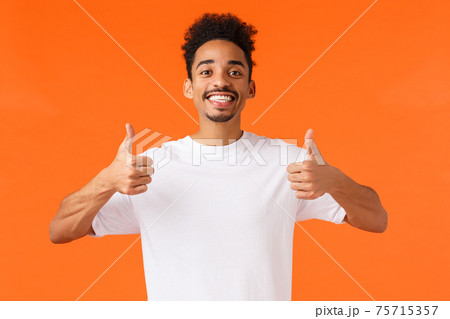 Optimistic, enthusiastic african-american male in white t-shirt, fully agree, feeling happy and satisfied, had great vacation, give positive feedback awesome hotel, showing thumbs-up in approval Optimistic, enthusiastic african-american male in white t-shirt, fully agree, feeling happy and satisfied, had great vacation, give positive feedback awesome hotel, showing thumbs-up in approval 75715357
