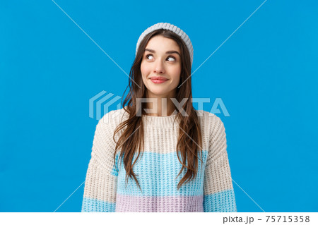 Girl curious what happening over corner, peeking and smiling excited, want see something interesting going on, standing blue background upbeat with lovely grin, wear winter sweater and hat Girl curious what happening over corner, peeking and smiling excited, want see something interesting going on, standing blue background upbeat with lovely grin, wear winter sweater and hat 75715358