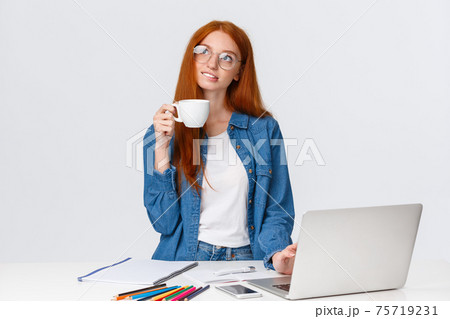 Dreamy, talented good-looking redhead girl studying design and art, looking dreamy and thoughtful up, creating new project, artwork, standing with cup coffee near laptop and pencils 75719231