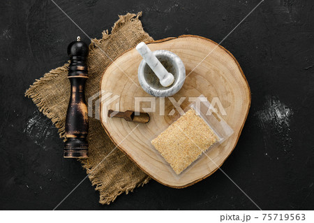 Wooden cross section with garlic in plastic package and mortar and mill 75719563