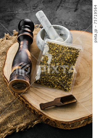 Wooden cross section with lemon pepper in plastic package and mortar and mill 75719564