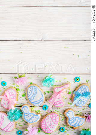 Sugar sprinkles and Easter frosted cookies in shape of egg chicken and rabbit on white wooden table background. Flat lay vertical mockup with copy space. 75721249