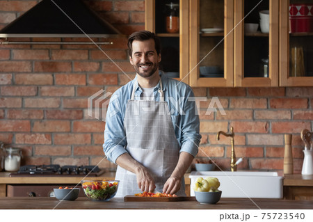 Portrait of smiling man cooking in home kitchen Portrait of smiling man cooking in home kitchen 75723540