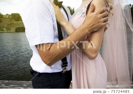 Creative hipster wedding by the sea. The bride is in a pink dress and veil, the groom is in beautiful trousers with suspenders and a youth shirt. Madness, fun and an unusual approach to marriage Creative hipster wedding by the sea. The bride is in a pink dress and veil, the groom is in beautiful trousers with suspenders and a youth shirt. Madness, fun and an unusual approach to marriage 75724485