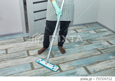 Bearded man in gloves with mop in hand cleaning floor in the house Bearded man in gloves with mop in hand cleaning floor in the house 75724712