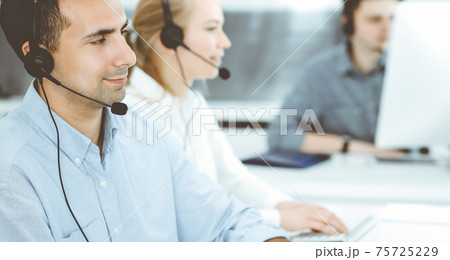Call center. Group of casual dressed operators at work. Adult businessman in headset at customer service office. Telesales in business Call center. Group of casual dressed operators at work. Adult businessman in headset at customer service office. Telesales in business 75725229