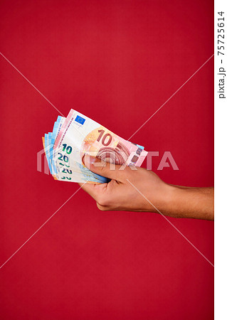 Man's hand holding and showing European union banknote Euro money isolated on red background 75725614