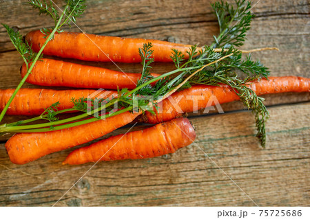 Flat lay of fresh carrot with roots on wooden background 75725686