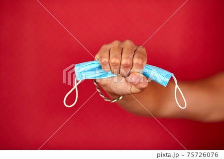 Men Hand holding a protection medical mask on red studio background 75726076