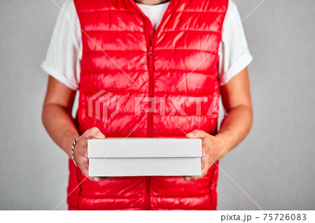 Delivery man employee in red vest uniform hold empty cardboard box 75726083