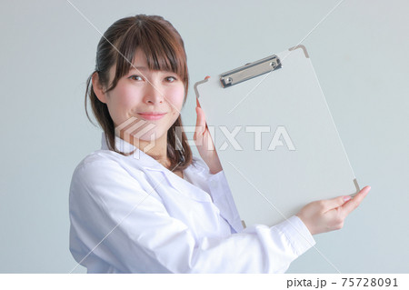 クリップボードを斜めに持つ白衣女性 クローズアップの写真素材