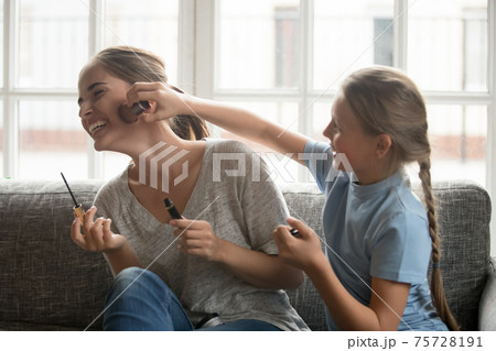 Happy small daughter and young mom have fun doing makeup Happy small daughter and young mom have fun doing makeup 75728191