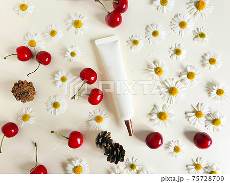 Face and eye cream squeeze cosmetic tube with long nozzle and bronze screw cap and camomiles, cherry berries and fir cones on ivory background. Cosmetics spa branding mockup, flatlay. Face and eye cream squeeze cosmetic tube with long nozzle and bronze screw cap and camomiles, cherry berries and fir cones on ivory background. Cosmetics spa branding mockup, flatlay. 75728709