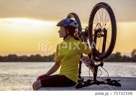 girl cyclist with a bicycle on the nature. Healthy lifestyle and sport. Leisure and hobbies girl cyclist with a bicycle on the nature. Healthy lifestyle and sport. Leisure and hobbies 75732506