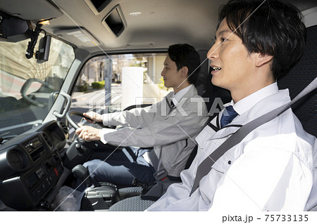 トラックの助手席に座る男性と運転席に座る男性 75733135