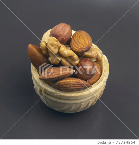 Different nuts in a waffle basket on a gray background. Vitamin wholesome food. Different nuts in a waffle basket on a gray background. Vitamin wholesome food. 75734854