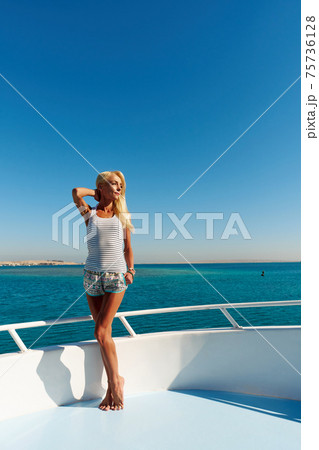 Young woman standing onth the deck of a boat in open sea at sunny summer day 75736128